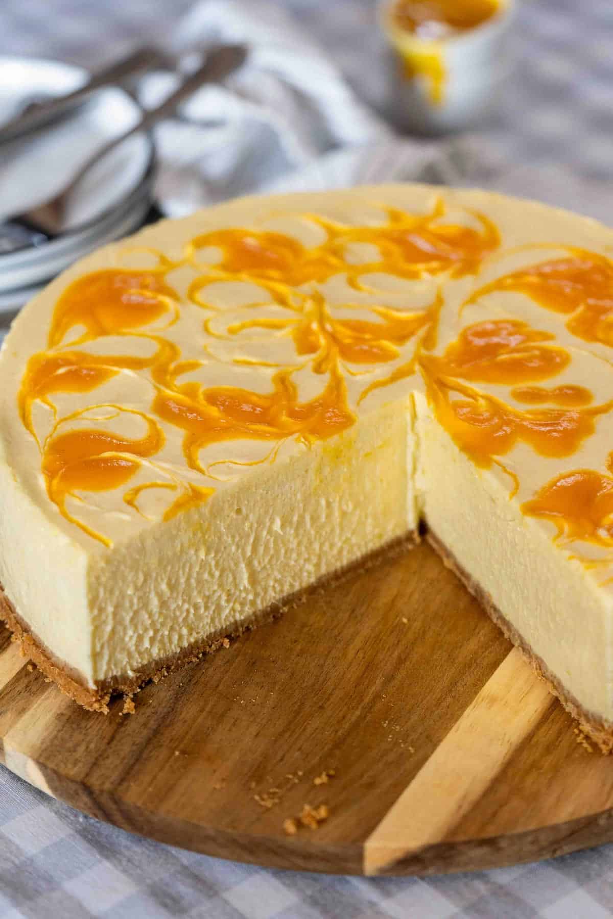 Whole no bake mango cheesecake on a serving board.